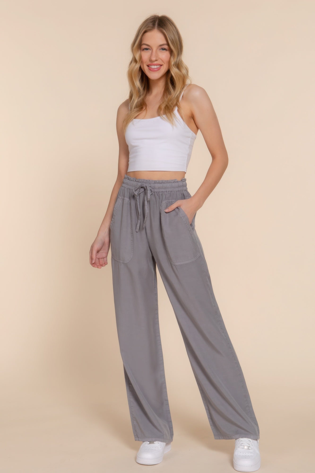 Woman wearing gray elastic waist Tencel long pants with a white tank top, showcasing a stylish and comfortable casual look.