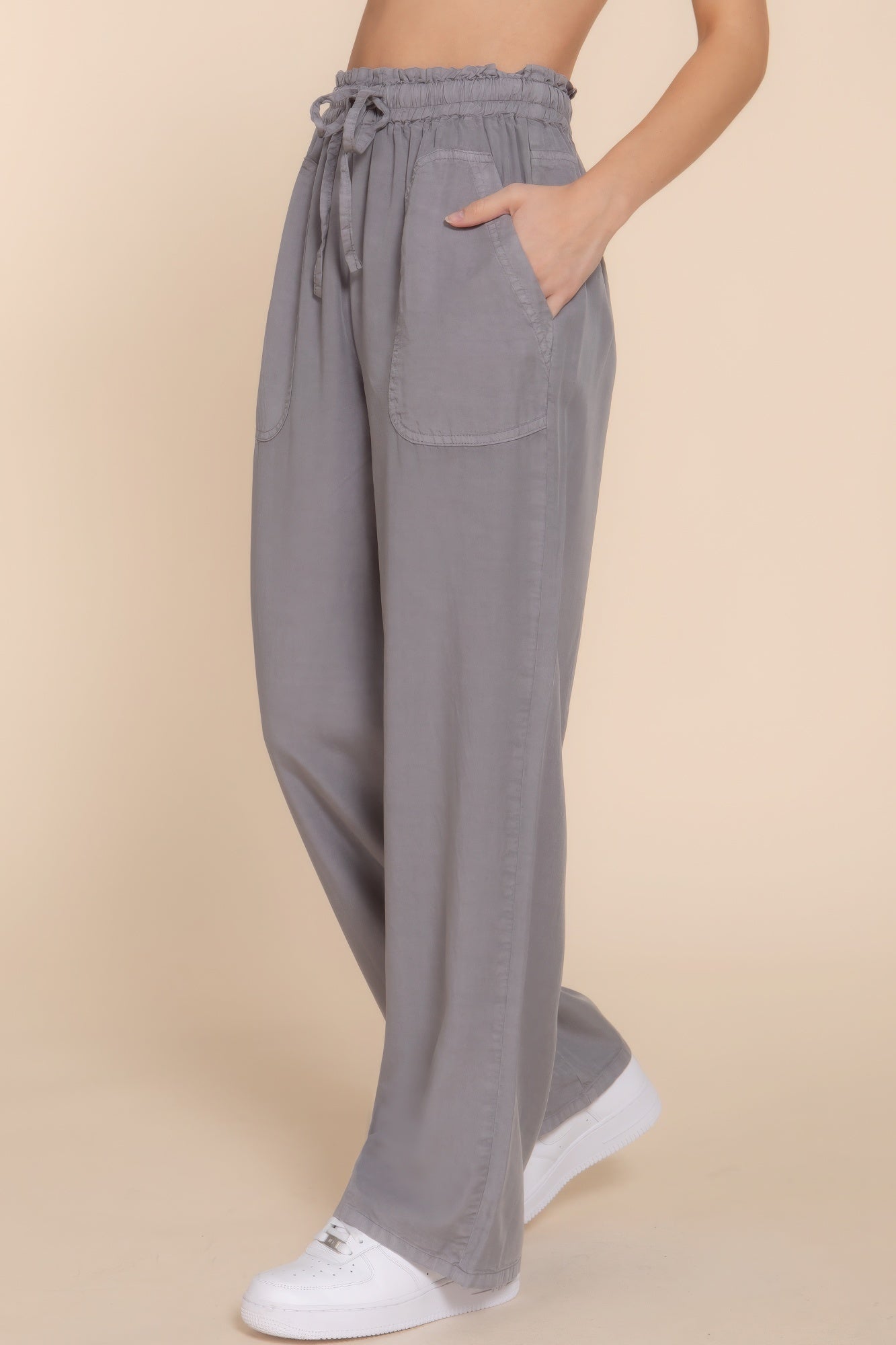 Woman wearing grey elastic waist Tencel long pants with pockets, paired with white sneakers, showcasing casual and versatile style.