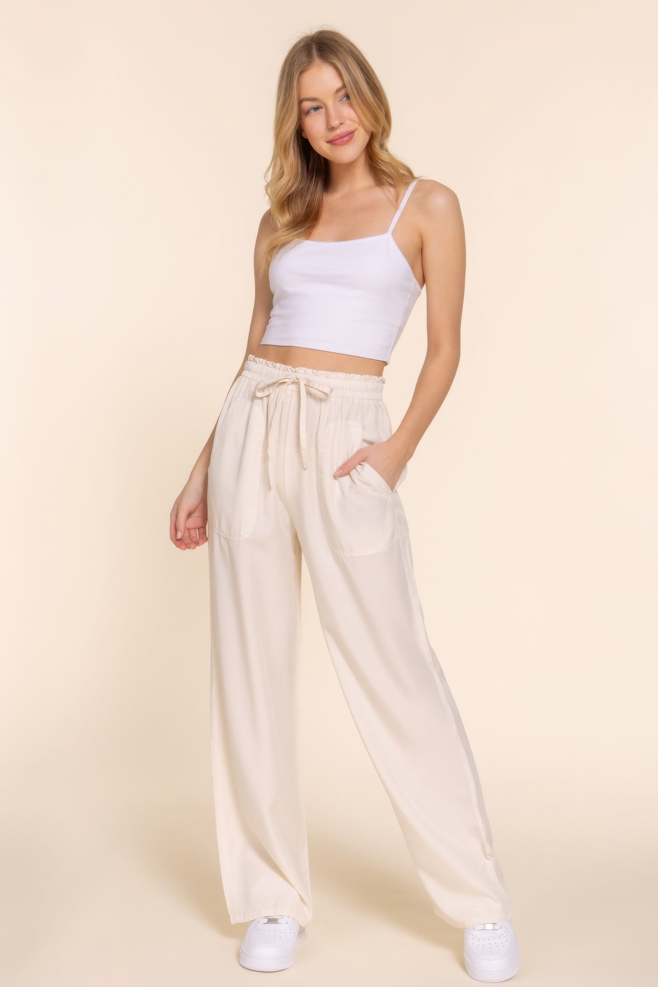 Woman wearing elastic waist Tencel long pants in beige, styled with a white crop top, showcasing casual elegance and comfort.