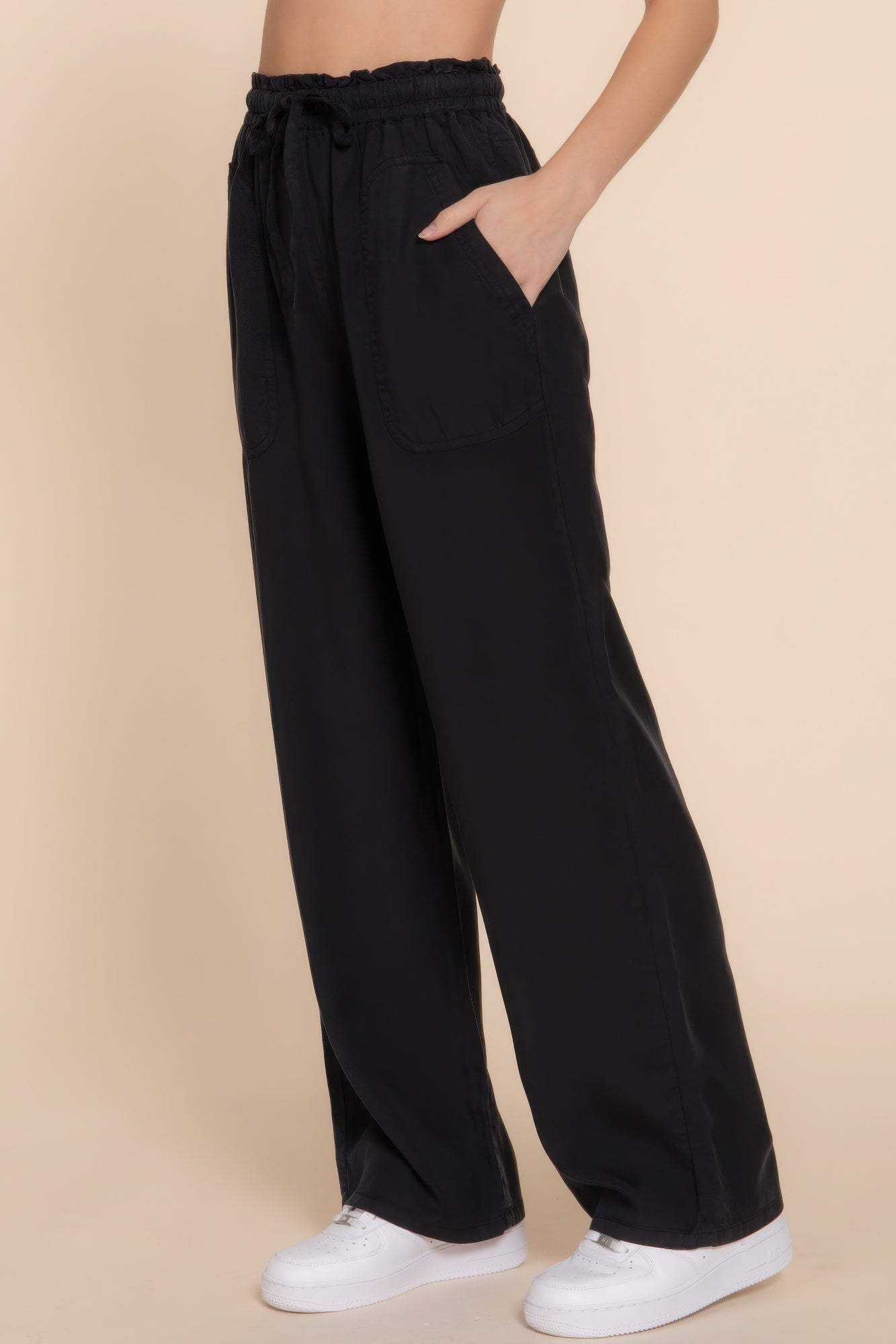 Black elastic waist Tencel pants for women, featuring a comfortable fit and versatile style, paired with white sneakers.