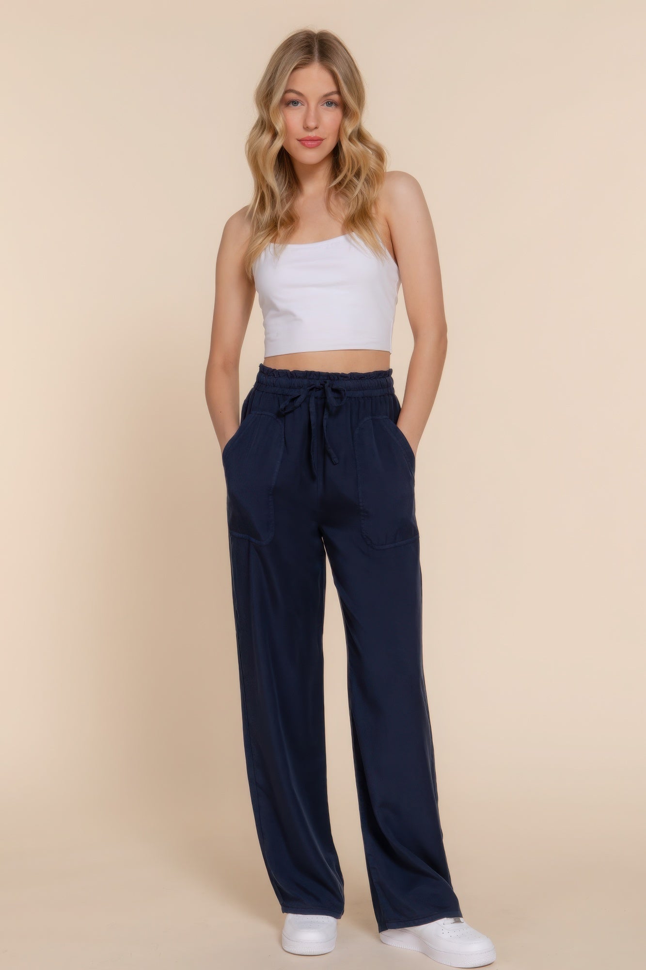 Woman wearing navy Tencel long pants with elastic waist, paired with a white top; showcasing versatile, comfortable style.