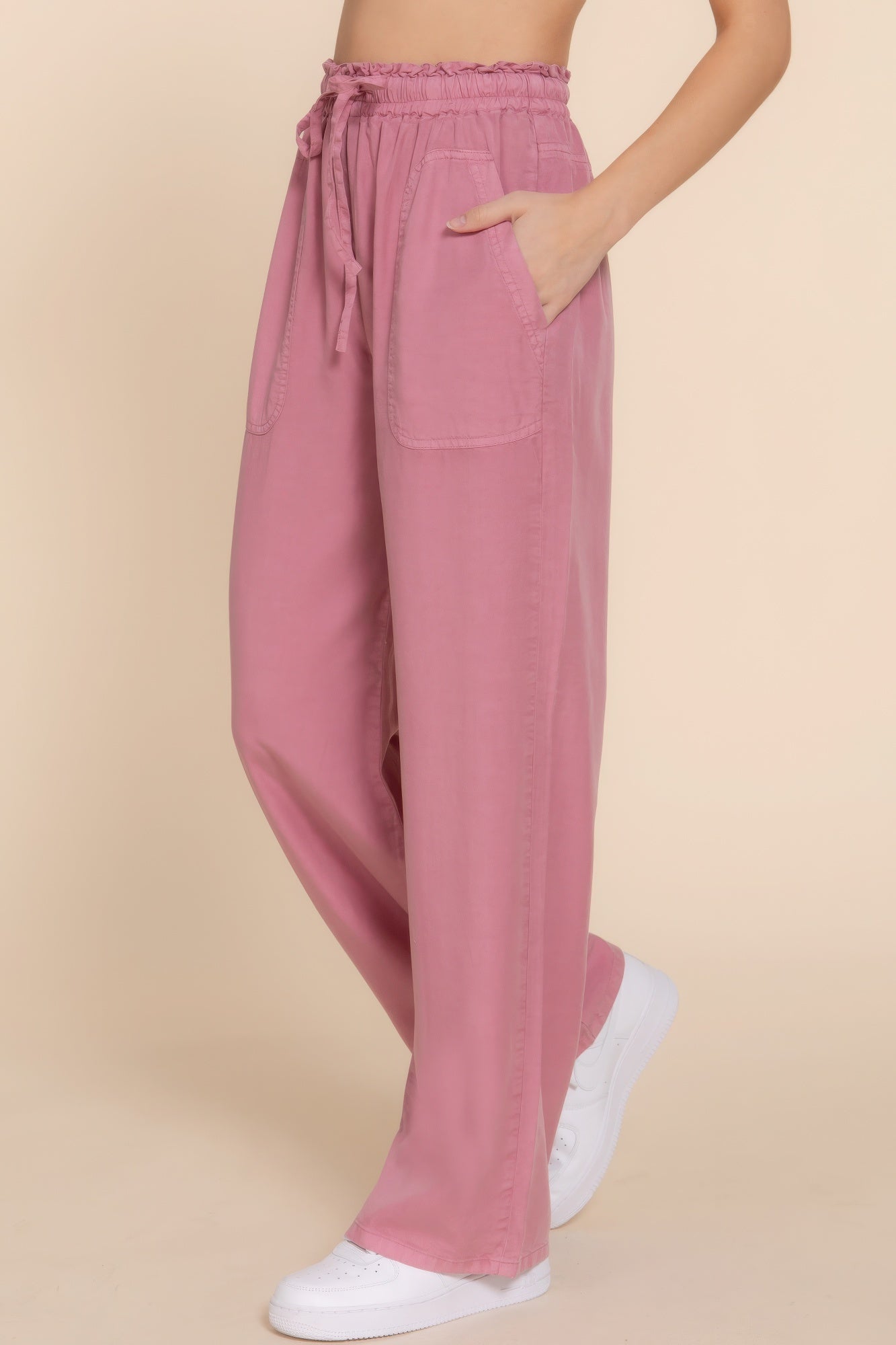 Pink elastic waist Tencel long pants with pockets, showcasing soft and breathable fabric, styled with white sneakers for a casual look.