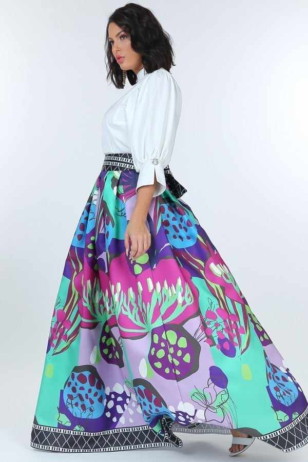 Woman wearing a puff sleeve blouse with pearl buttons and a vibrant floral maxi skirt.