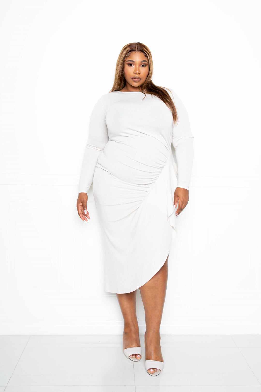 Plus-size model wearing creamy asymmetrical sweater dress with waterfall ruffle.