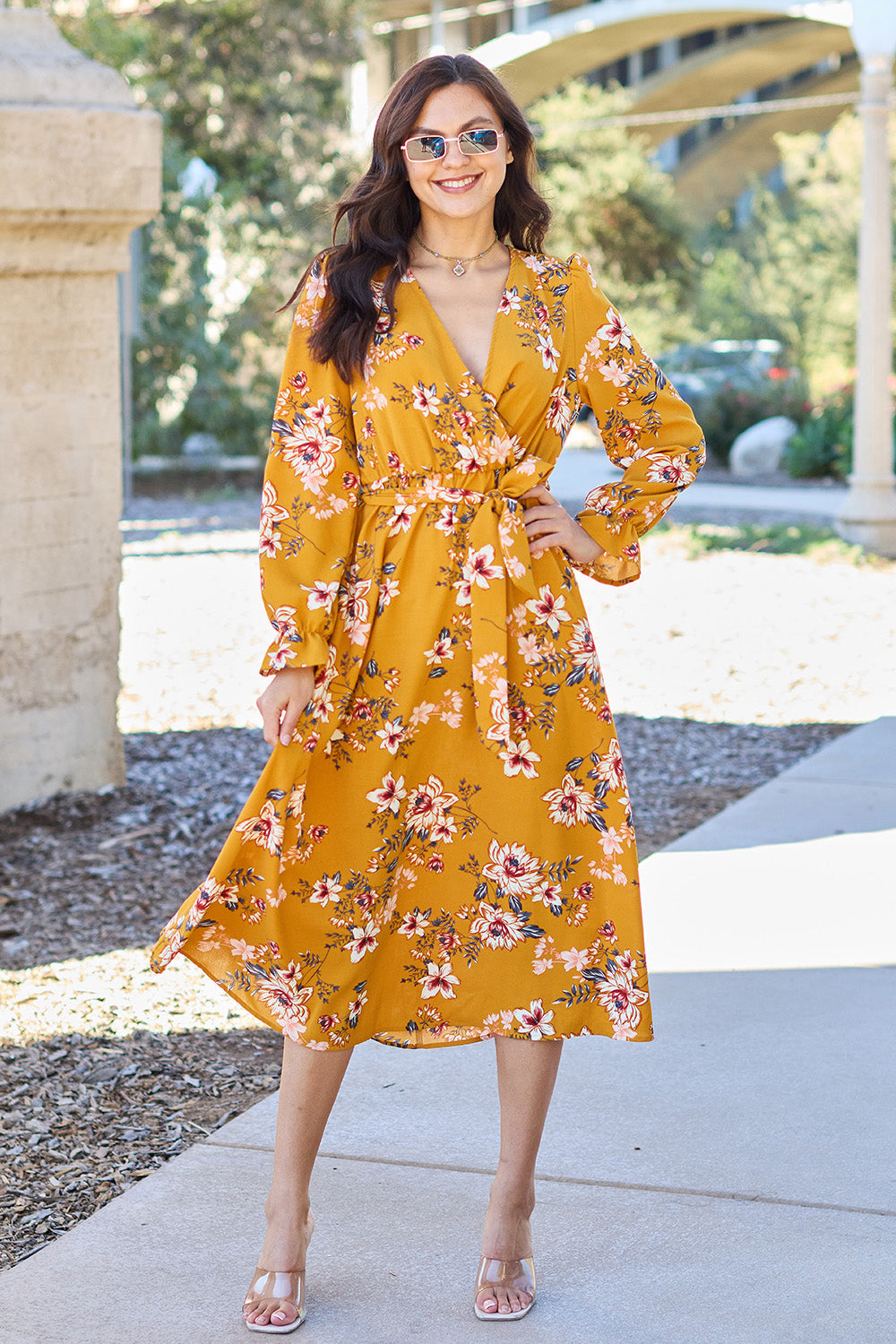 Woman wearing a floral tie back flounce sleeve dress with a vibrant yellow print, perfect for a stylish summer look.