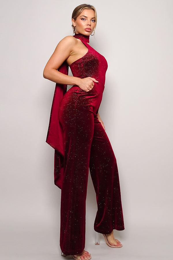 Glitter Velvet Jumpsuit with one-shoulder design and wrap-around scarf detail, featuring a flattering fit and long pants.