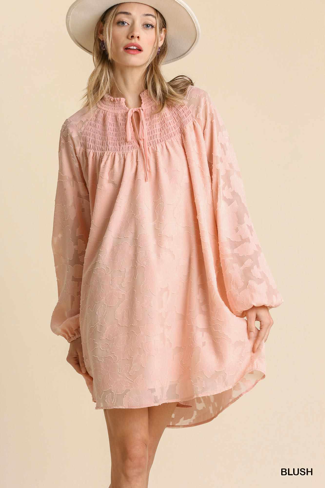 Woman wearing blush Jacquard Tie Neck Yoke Dress with hat, 100% cotton, smocked design, available in sizes S, M, L.