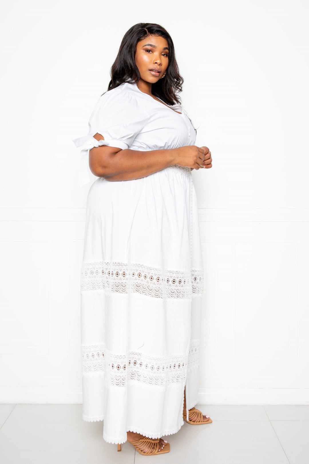 Woman wearing a white puff sleeve maxi dress with lace insert, showcasing elegant plus-size fashion.