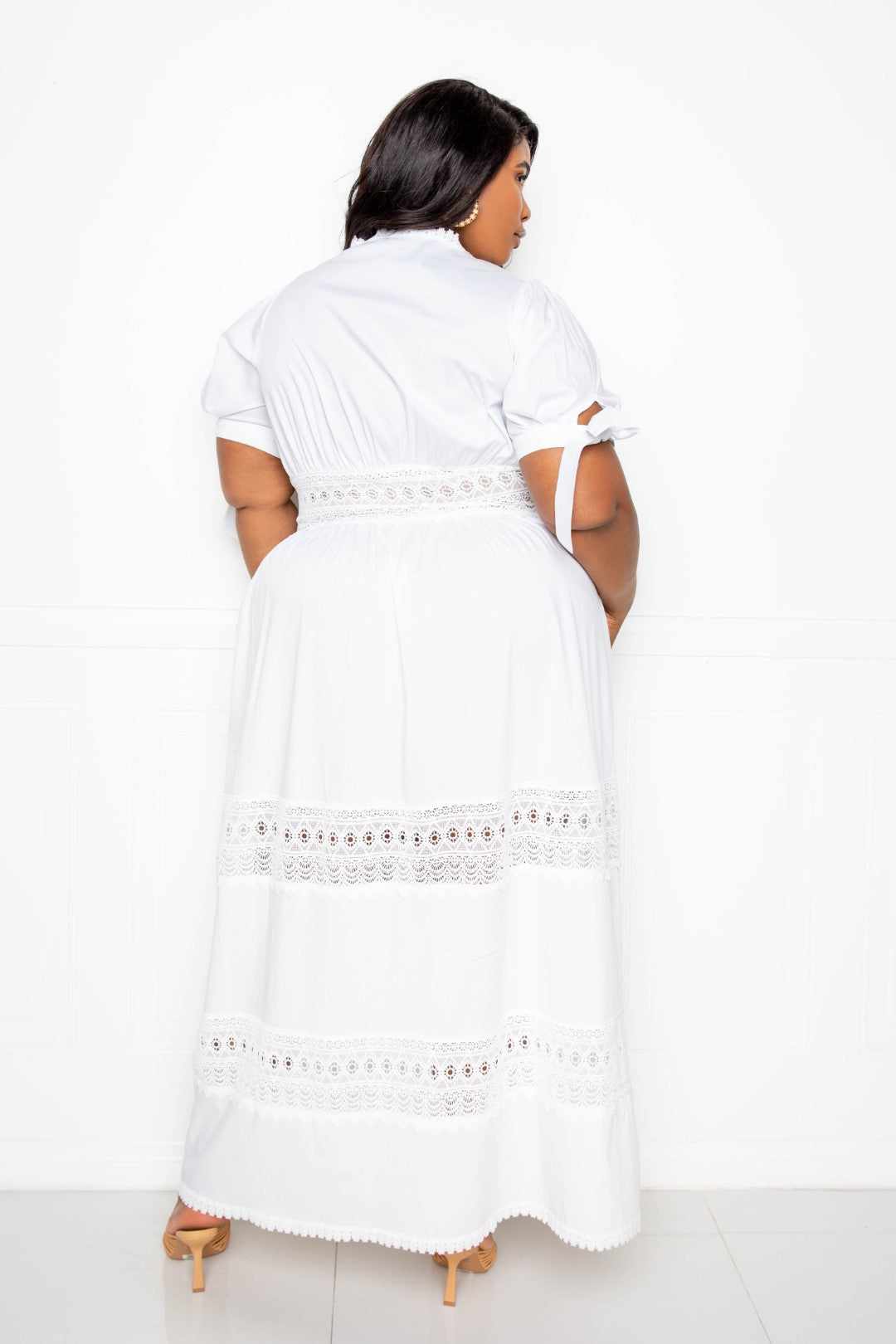 Plus size model in white puff sleeve maxi dress with lace insert, back view.