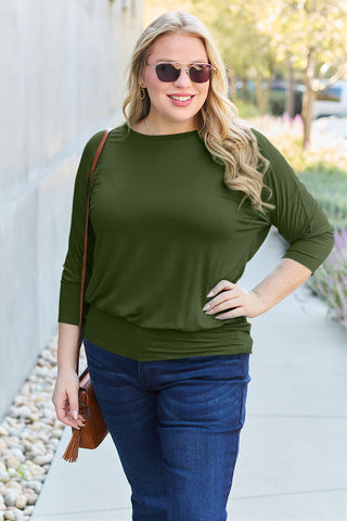 Woman in green round neck batwing sleeve top with sunglasses, styled for casual outdoor wear.