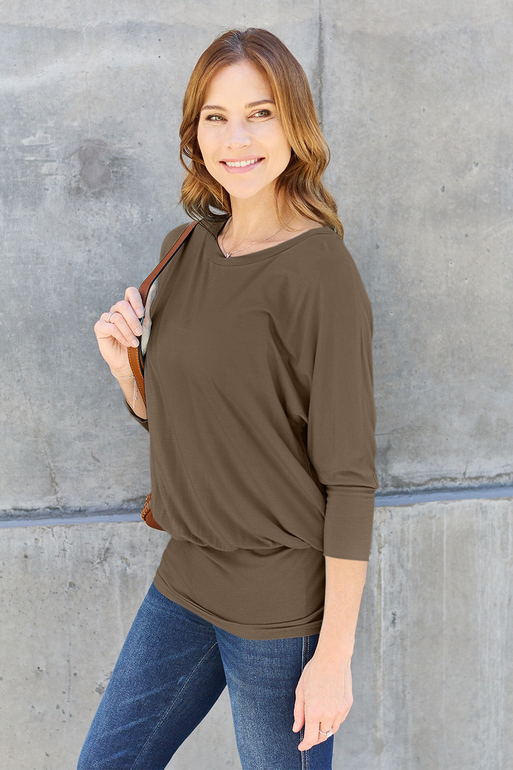 Woman wearing a round neck batwing sleeve top in brown, paired with jeans, showcasing casual style fashion suitable for everyday wear.