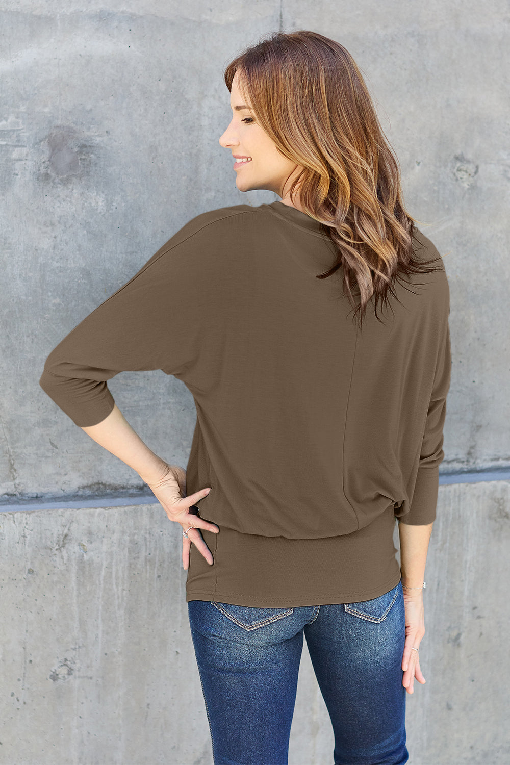 Woman wearing a round neck batwing sleeve top in olive green, slightly stretchy, made of rayon and spandex.