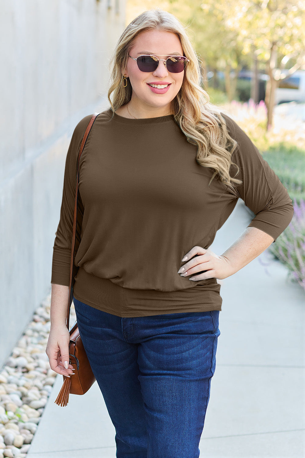 Woman wearing a round neck batwing sleeve top with slightly stretchy material, 95% rayon and 5% spandex, in a stylish outdoor setting.