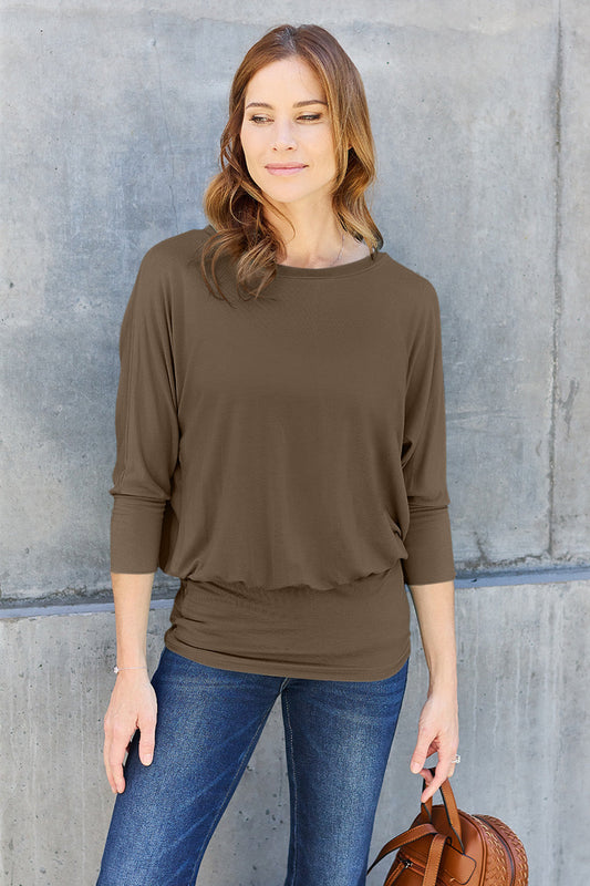 Woman wearing a round neck batwing sleeve top with jeans, showcasing a casual chic style.