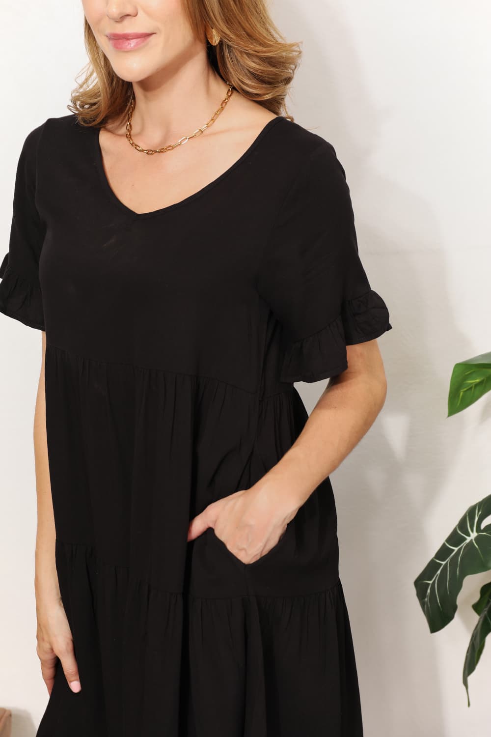 Woman wearing elegant black V-neck flounce sleeve tiered dress with A-line hem, perfect for day to night transitions.