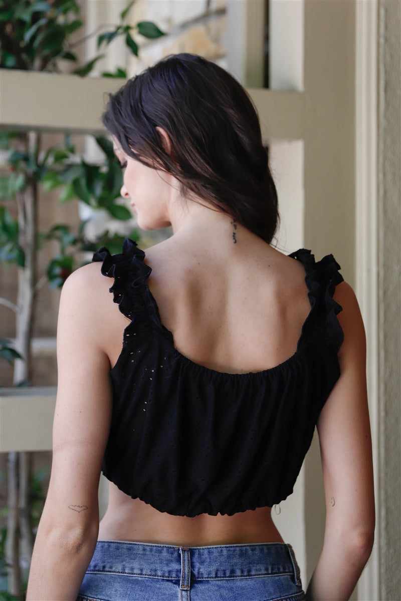 Woman wearing black embroidered sleeveless crop top with ruffled straps and drawstring-adjustable hem, seen from the back.