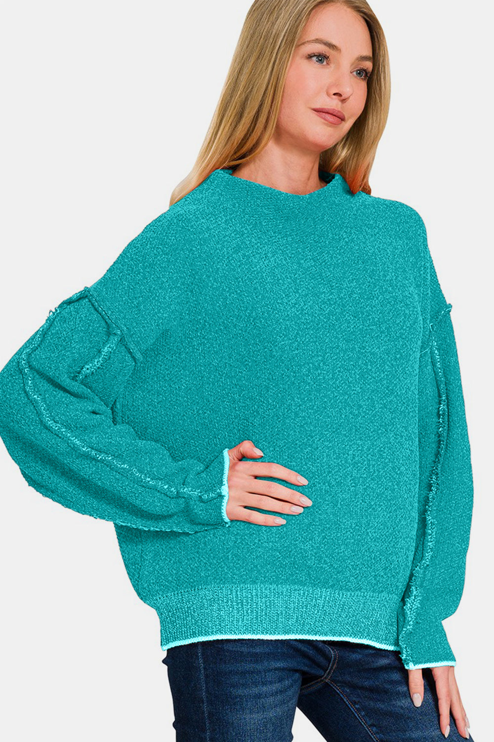 Exposed seam mock neck long sleeve sweater in turquoise worn by a model, showcasing casual chic style and comfort.