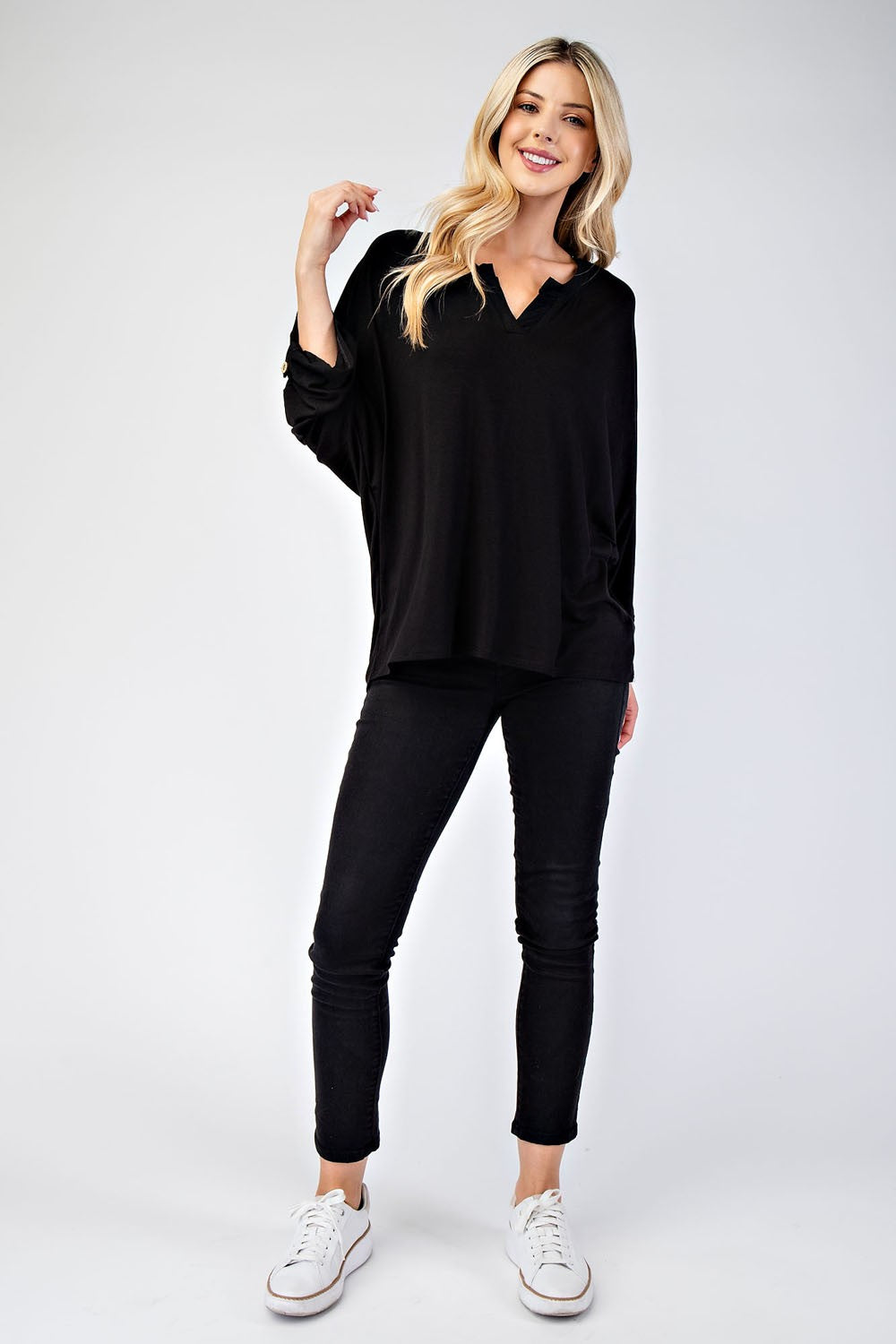 Woman wearing black full size notched three-quarter sleeve blouse with jeans and sneakers, showcasing casual fashion style.