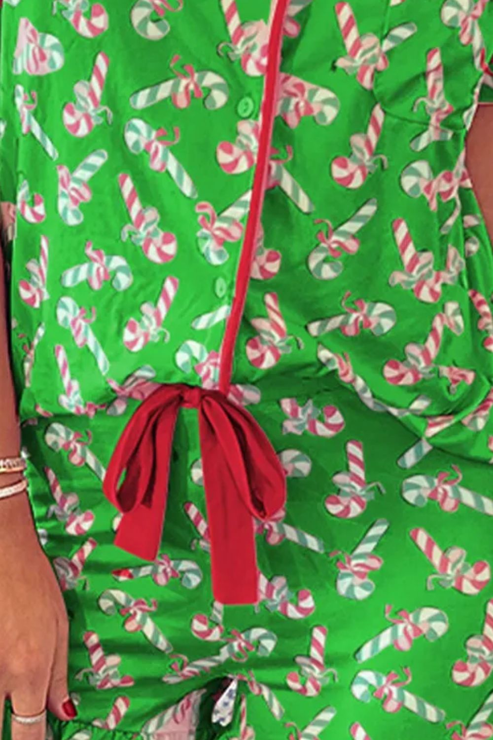 Green candy cane print collared neck top and shorts pajama set with red tie detail.