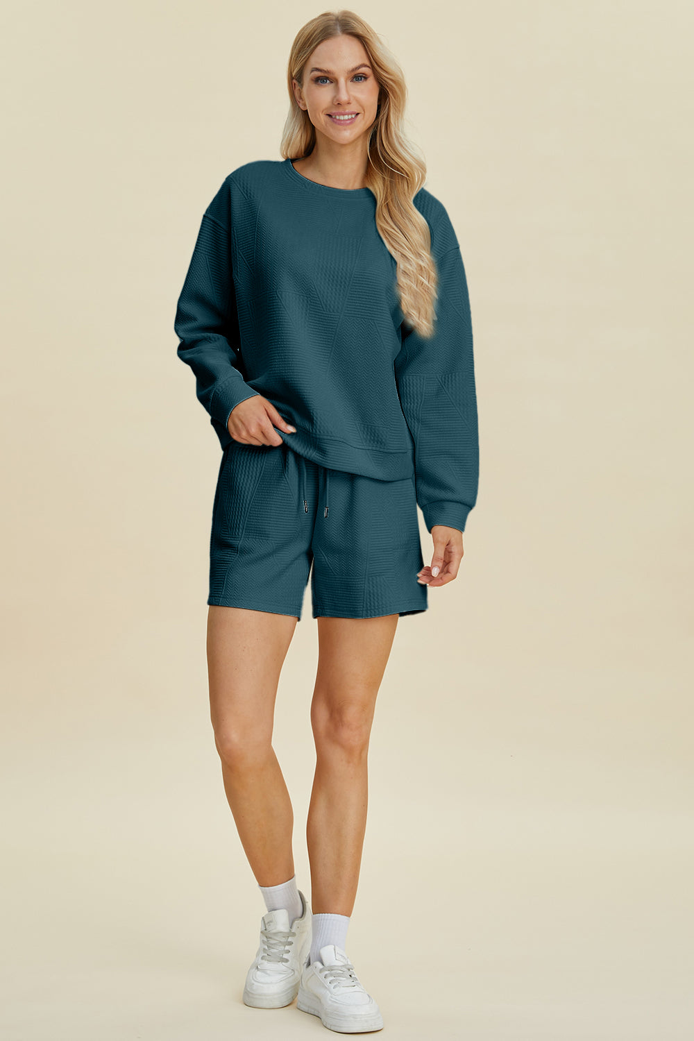 Woman wearing fall long sleeve top and shorts set with drawstring, made of slightly stretchy polyester and elastane blend.