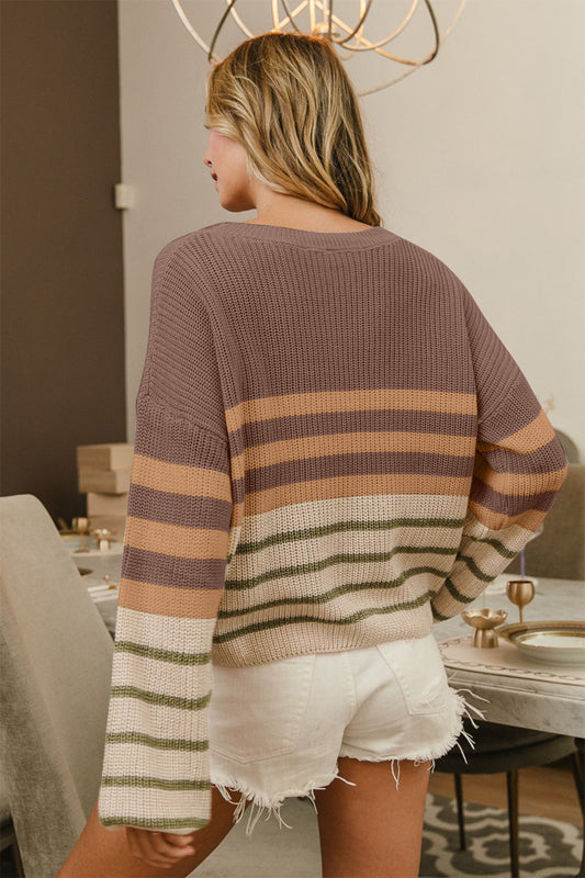 Woman wearing BiBi Color Block Striped Long Sleeve Sweater in neutral tones with white shorts, standing in a chic dining room.