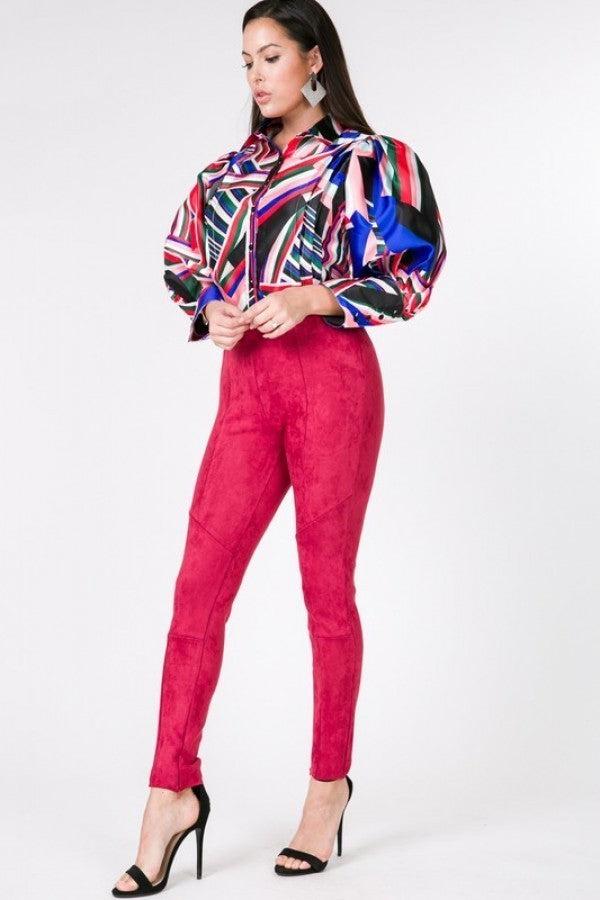 Woman wearing deep red faux suede skinny pants and colorful blouse with high heels.