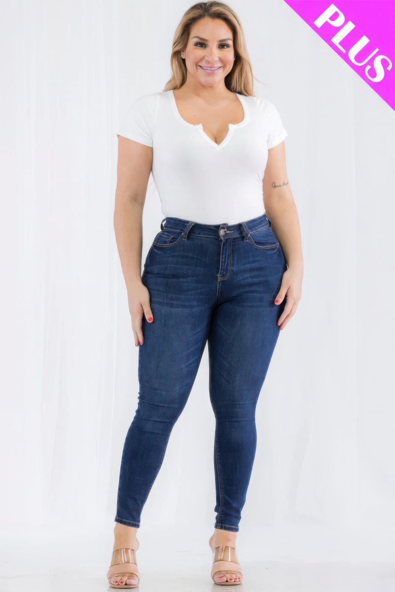 Plus size model in a white split neck short sleeve bodysuit and blue jeans, showcasing casual style and comfort in vibrant Poinciana color.