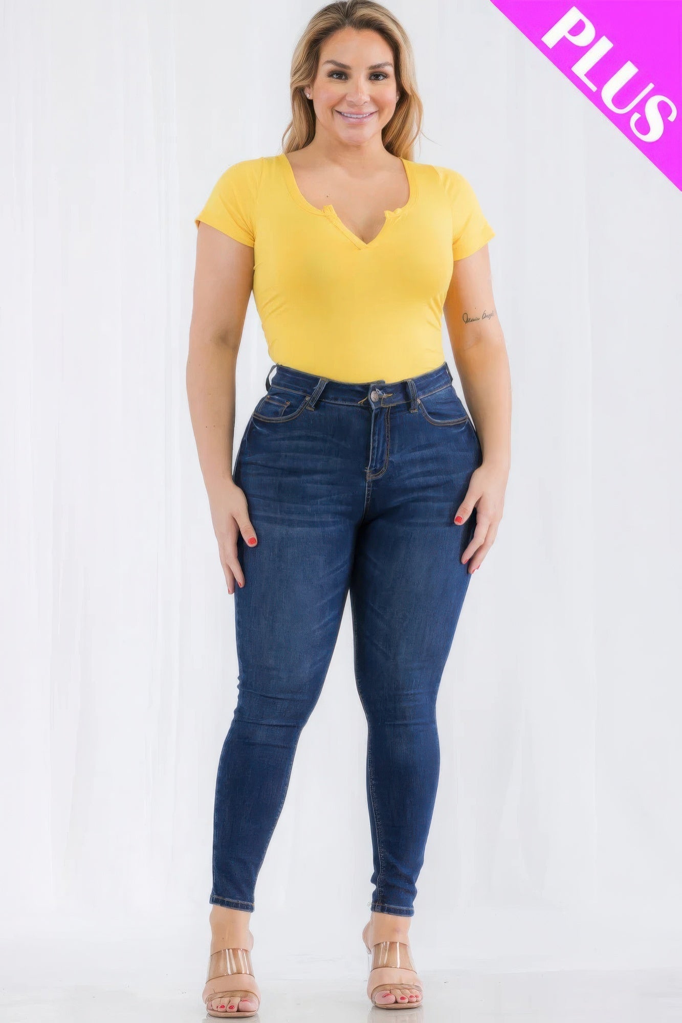 Plus size model wearing yellow split neck short sleeve bodysuit with jeans, showcasing trendy casual fashion for curvy figures.