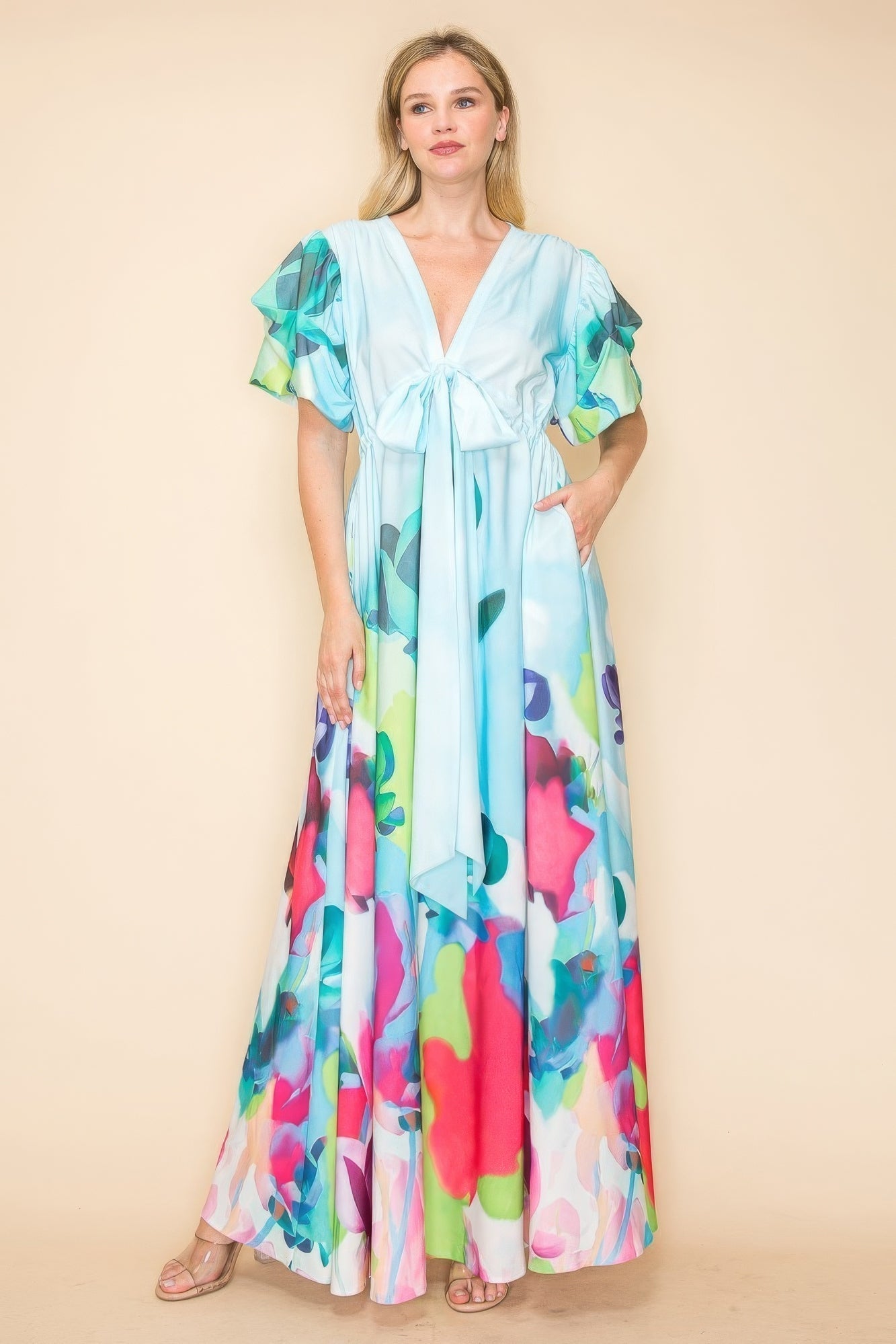 Woman wearing a vibrant multi-color printed V-neck maxi dress with a self-tie waist ribbon and pockets, perfect for casual or beach outings.