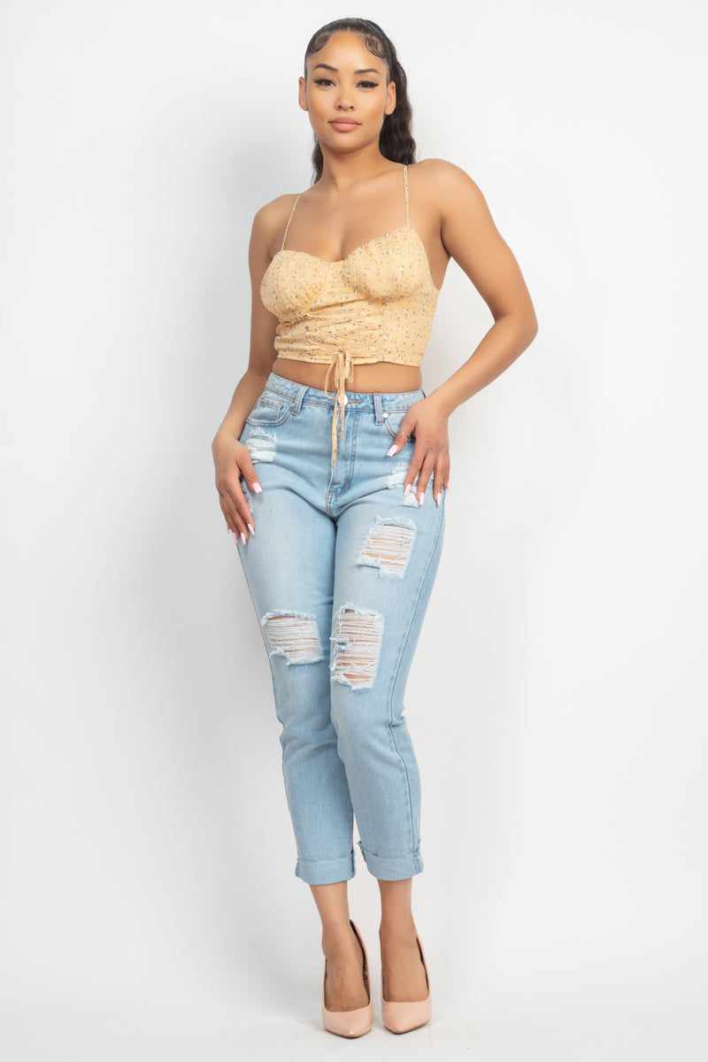 Woman wearing a yellow floral front tie top with sweetheart neckline and ripped jeans, showcasing trendy casual fashion.