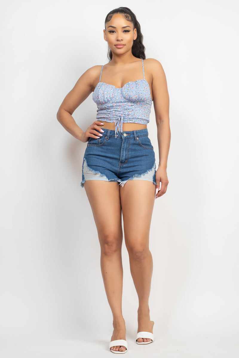 Woman wearing blue floral front tie top with sweetheart neckline and denim shorts, showcasing cropped summer look.