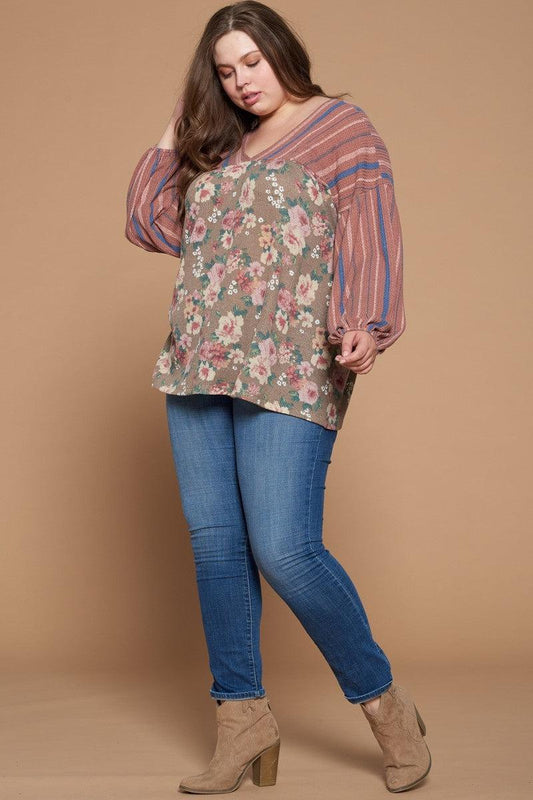 Plus-size model wearing a marsala floral printed knit top with long puffed sleeves, striped yoke, and v-neckline, paired with jeans.