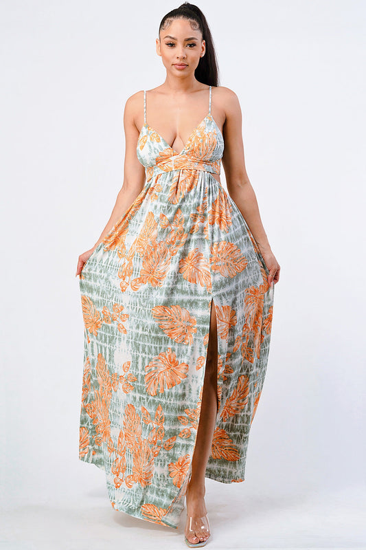 Woman wearing floral printed side slit maxi dress with orange and green patterns, sleeveless design, perfect for summer fashion.