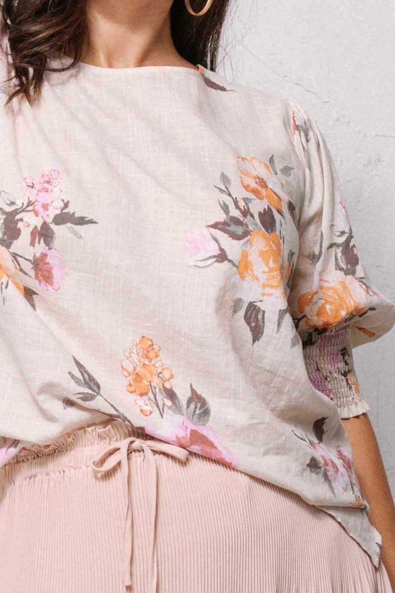 Floral printed woven blouse with round neckline and puffed sleeves, showcasing an eye-catching design in oatmeal color.