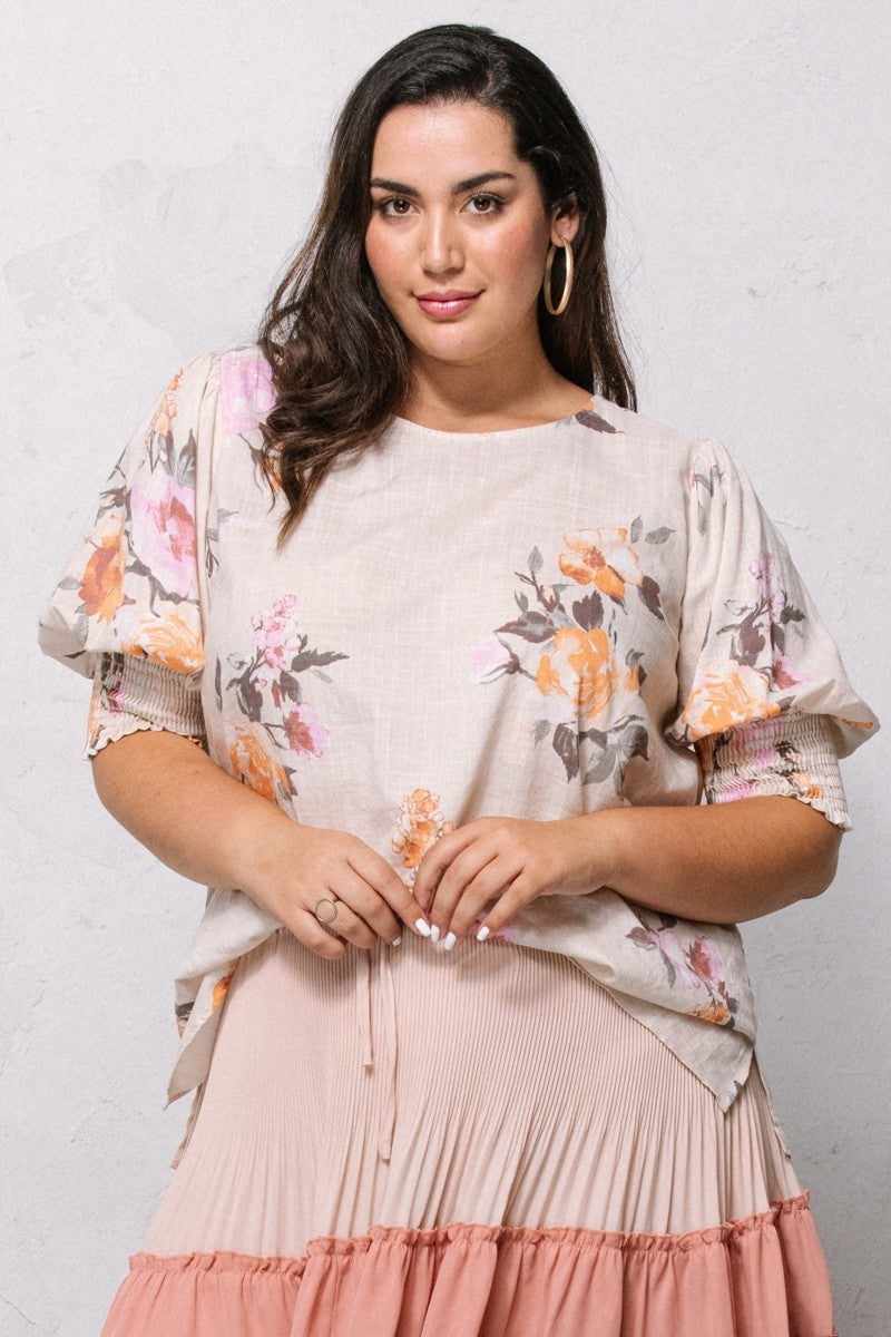 Woman wearing a floral printed woven blouse with puffed sleeves and a smocked hem, showcasing a chic and stylish look.