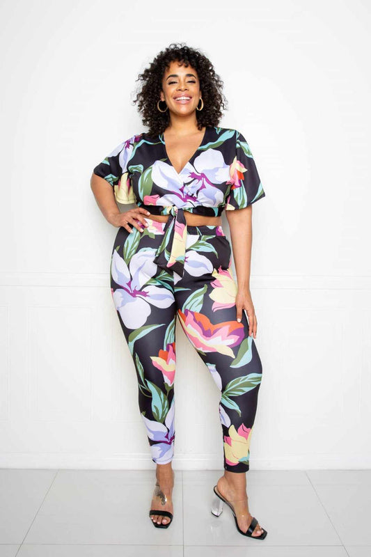 Plus-size model in a vibrant multi/black flower jogger and top set made from polyester and spandex, perfect for fashionable comfort.