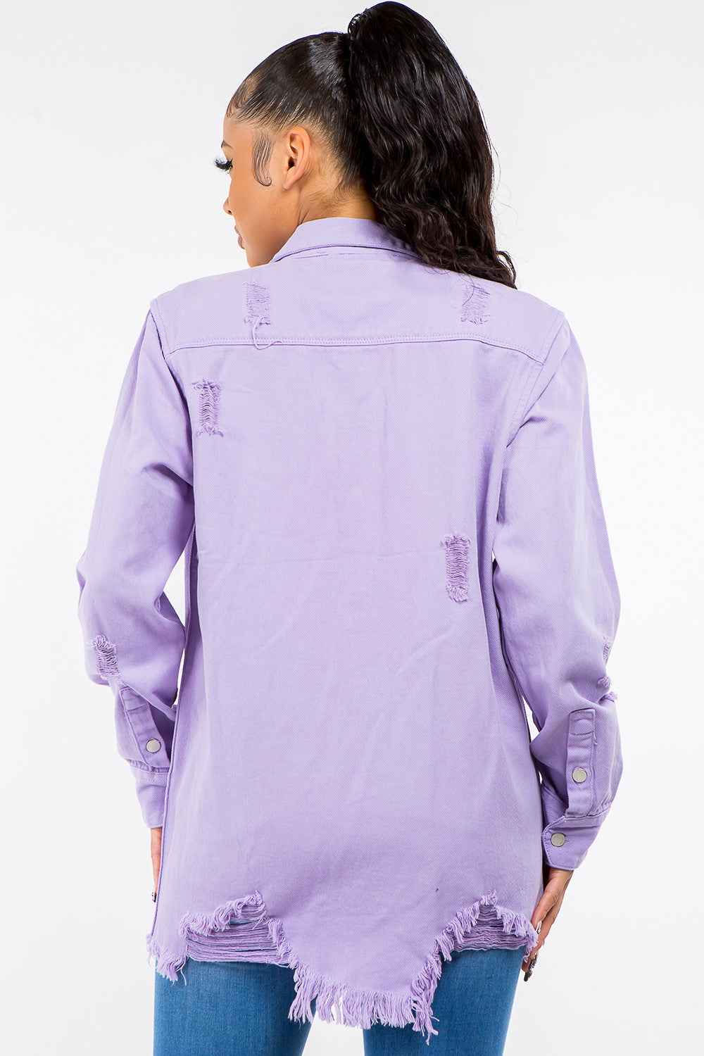 Woman wearing a lavender frayed hem distressed denim jacket showing edgy back details and casual style.