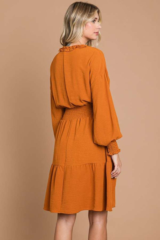 Woman wearing an orange frill smocked mini dress with lantern sleeves, highly stretchy polyester fabric, perfect for stylish outfits