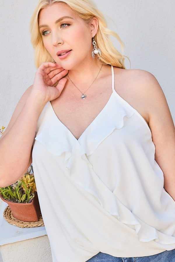 Plus-size model wearing a front surplice ruffle cami top in white, paired with jeans, showcasing the top's design and fit.