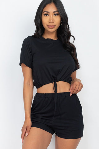 Woman wearing black front tied crop top and shorts set made of soft jersey fabric, perfect for casual summer wear.