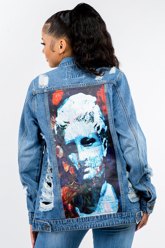 Woman wearing a full-size distressed denim jacket with a bold artistic back print for an edgy, trendy look.