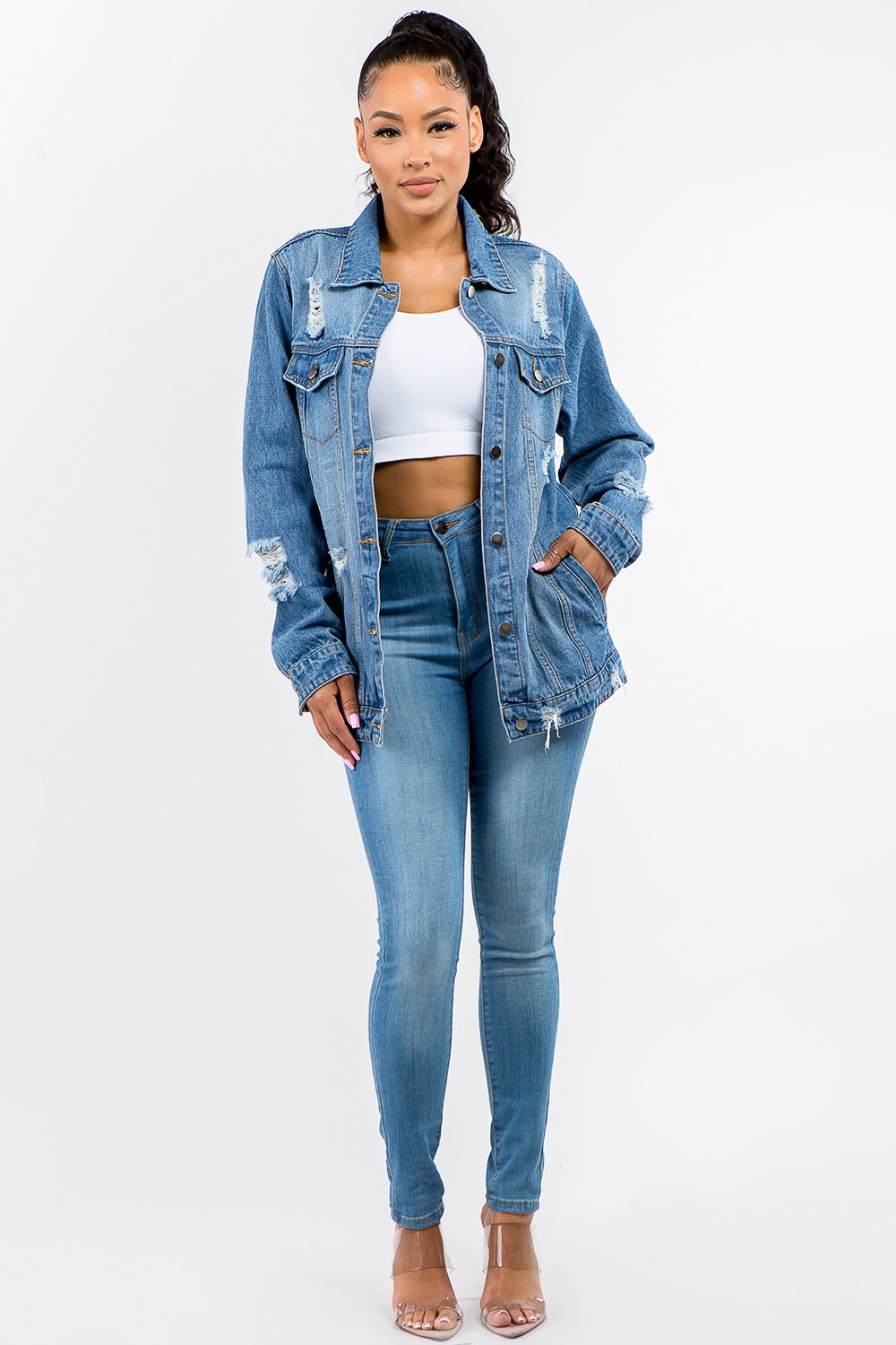 Full size button-up distressed denim jacket with edgy vibe, perfect for versatile styling, worn over a white top and jeans.