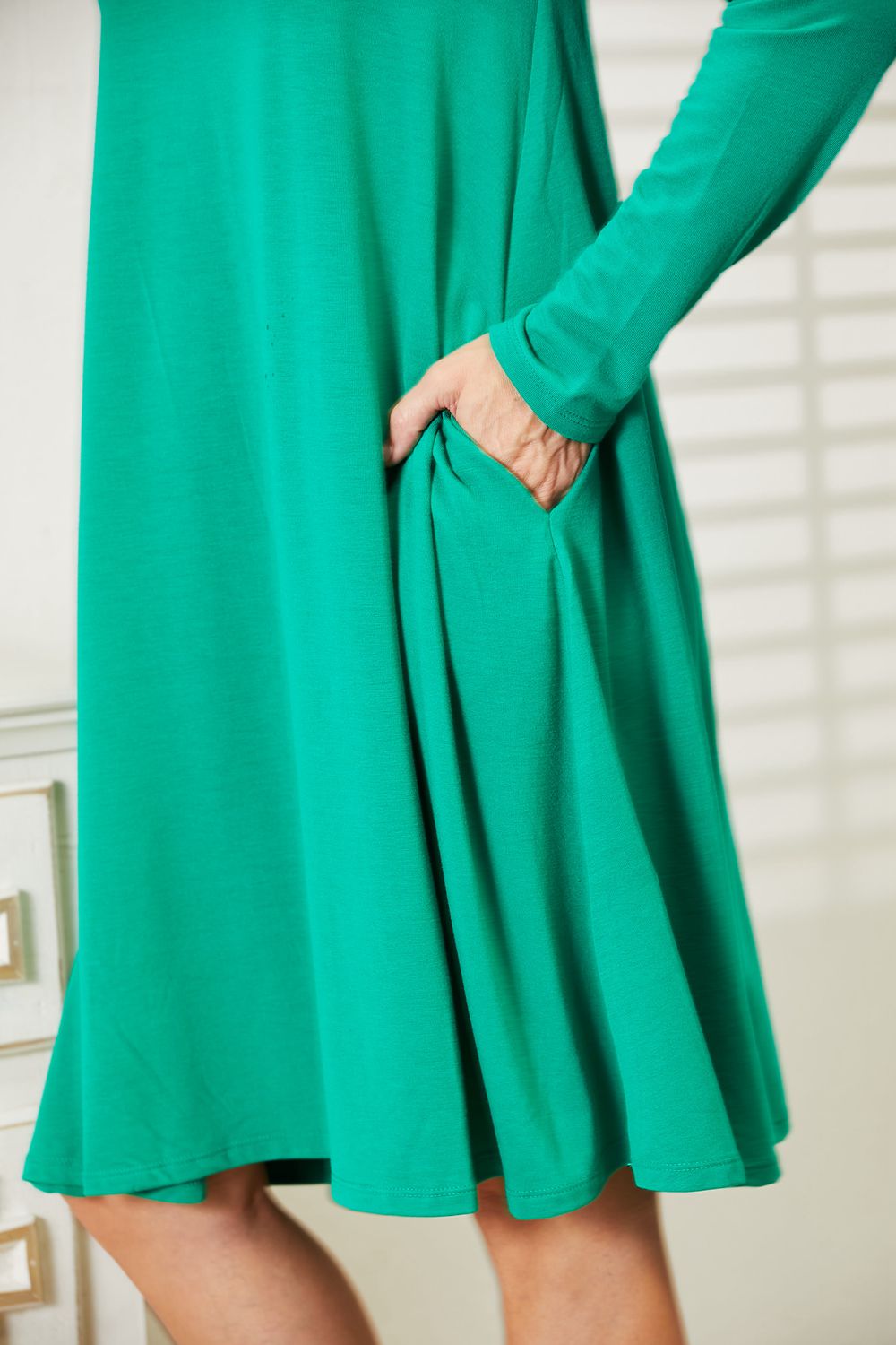 Green flare dress with long sleeves and pockets, made of stretchy polyester-rayon-spandex blend, showcasing comfort and style.