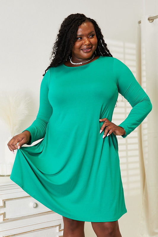 Woman wearing a full size green long sleeve flare dress with pockets, showing comfortable and stretchy fit.