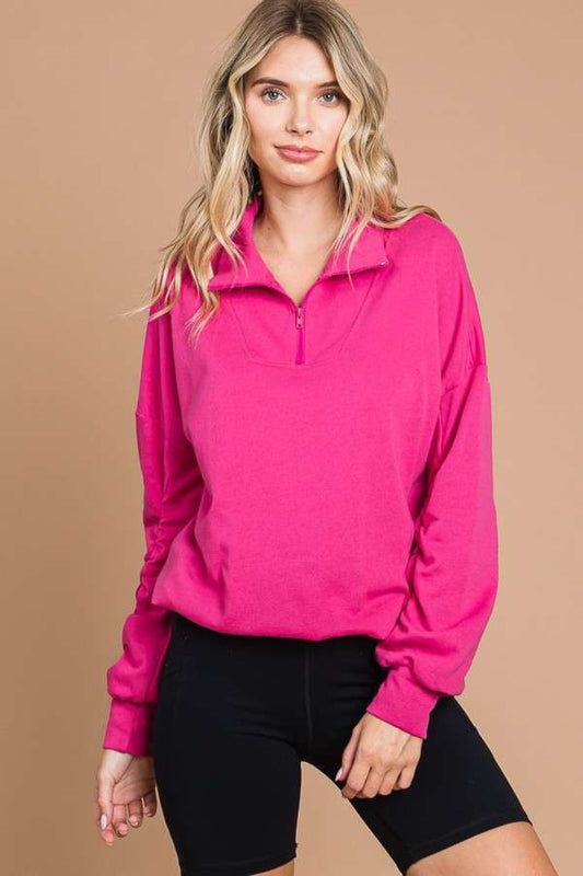 Woman wearing a pink full-size half zip long sleeve sweatshirt with black shorts, featuring a basic style, made of cotton and polyester.