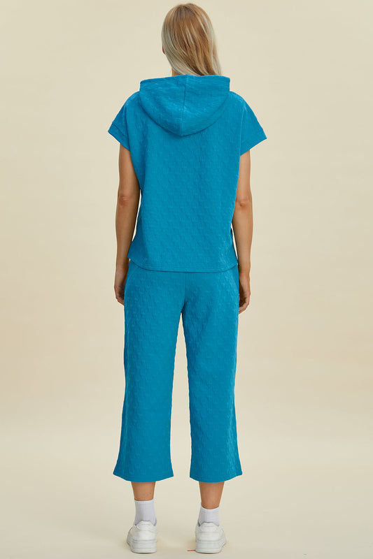 Woman wearing blue short sleeve hoodie and pocketed pants set, featuring drawstring and slight stretch, made of polyester and spandex.