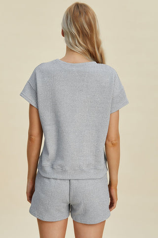 Woman wearing gray full-size texture short sleeve top and shorts set with pockets and drawstring.