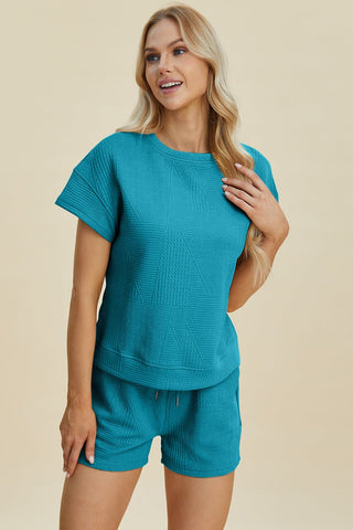 Woman wearing a turquoise full-size texture short sleeve top and shorts set with pockets and drawstring, made of polyester and elastane.