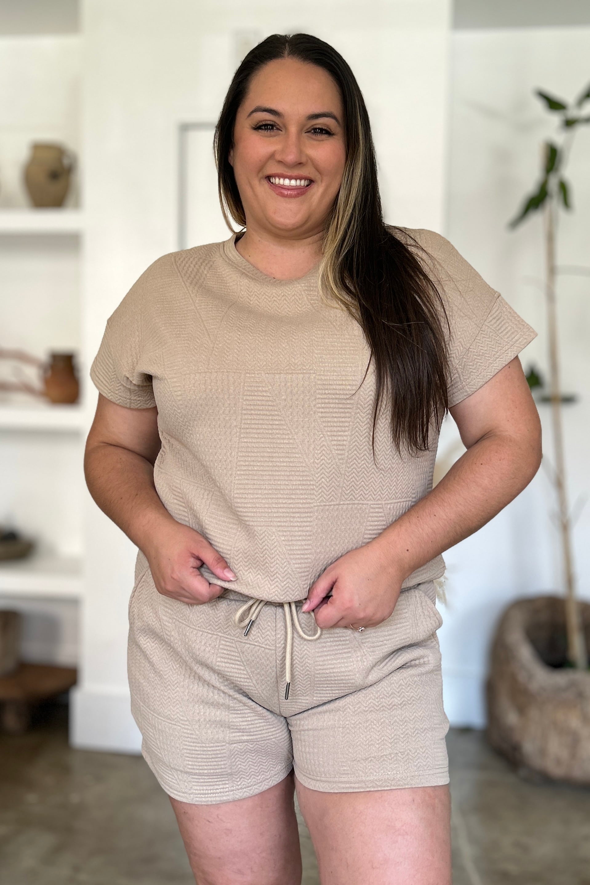 Woman wearing beige full size texture short sleeve top and shorts set with pockets and drawstring, made of polyester and elastane.