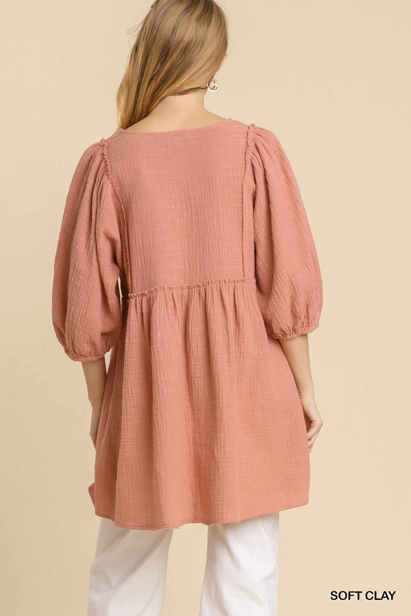 Woman modeling soft clay gauze slub tunic dress with frayed edges and V-neck design from back view.